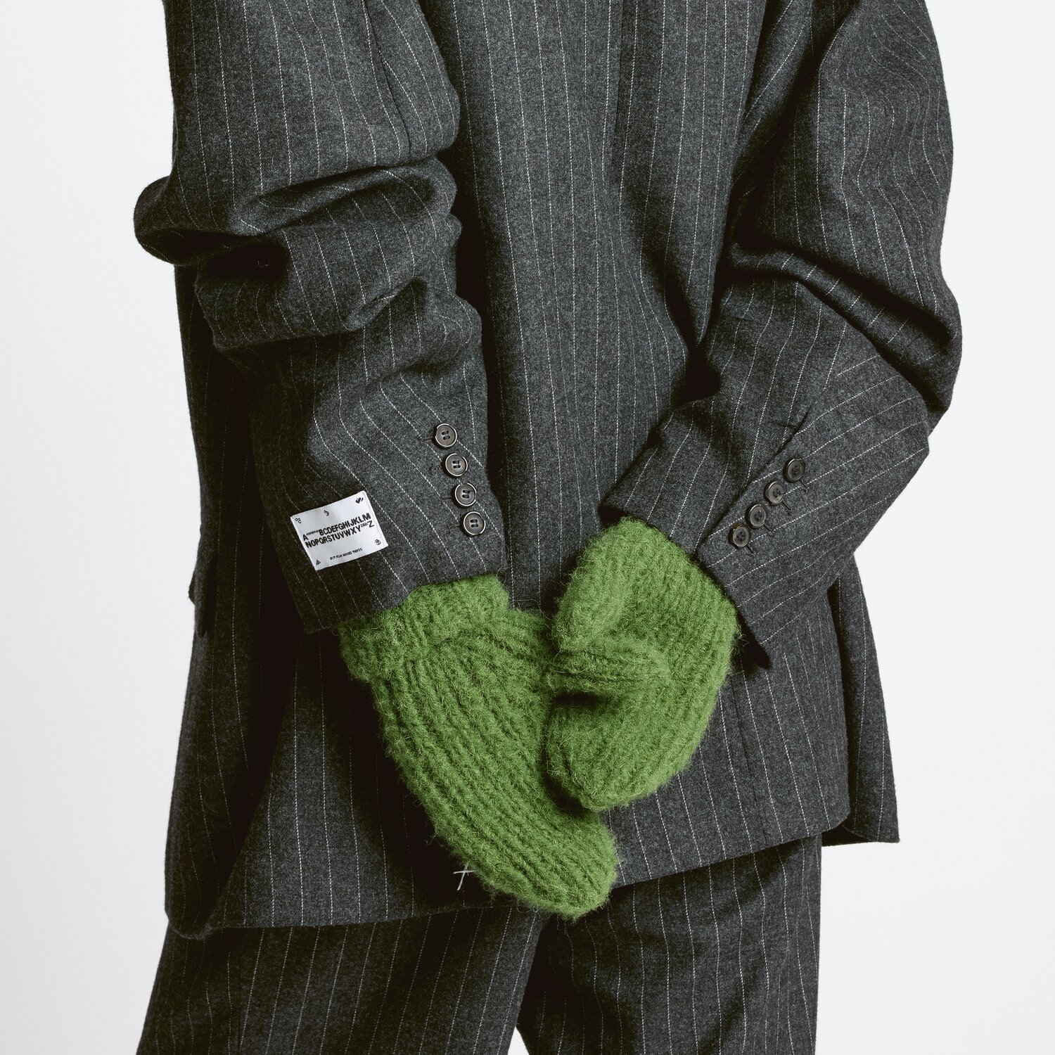 Strickset Handschuhe Modell 20: Grüne Fäustlinge aus Premium Natural Fibres, getragen zu grauem Anzug.