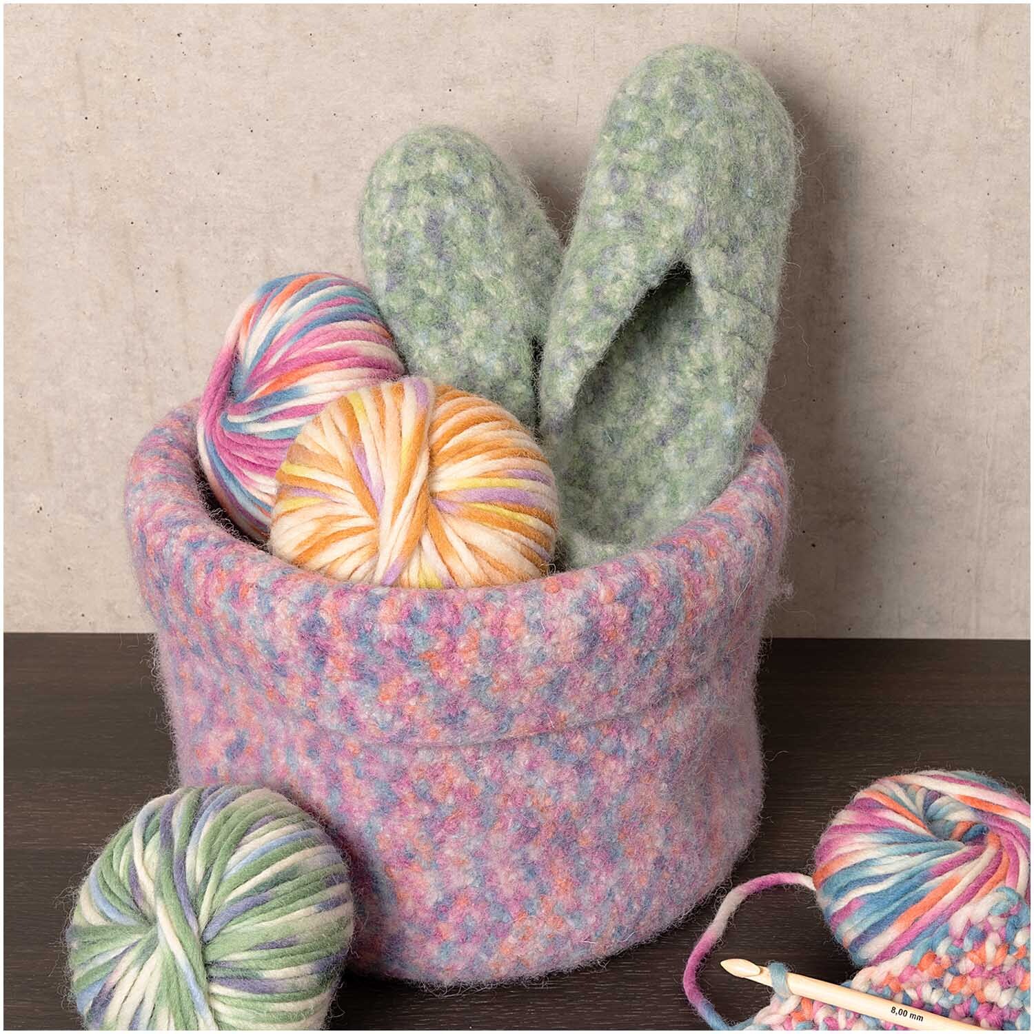 Creative Filz Print 50g 50m Farbe Blau Color von Rico Design Creative Filz Print: Ein Korb mit buntem Garn und gefilzten Hausschuhen, ideal für kreative Strickprojekte.