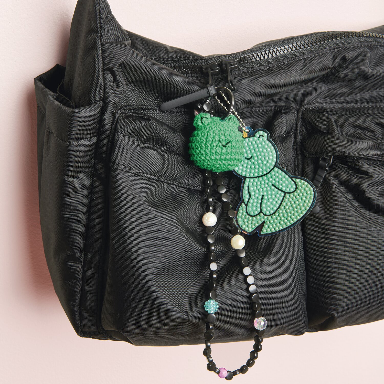 Ricorumi Häkelset Schlüsselanhänger - Chingu Animals: Grüner Häkelanhänger an schwarzer Tasche, verziert mit bunten Perlen.