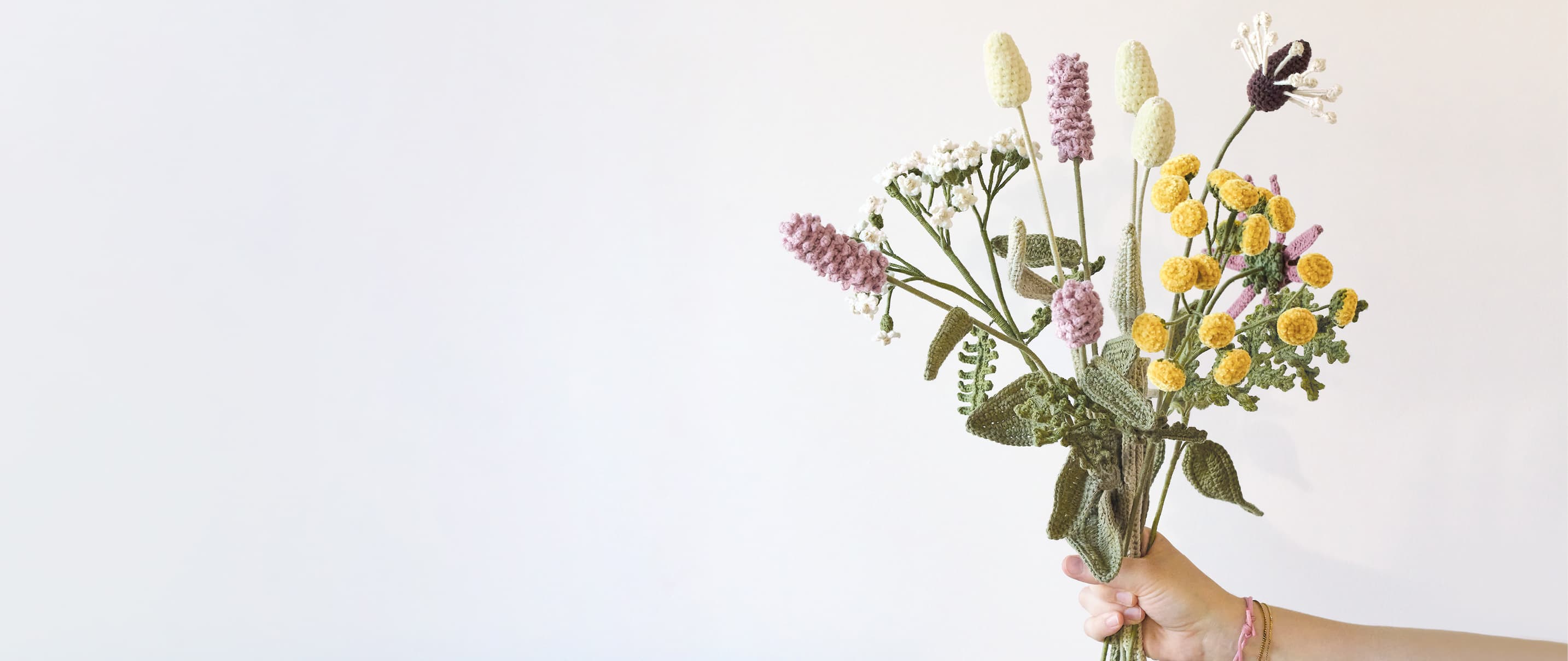 Hand hält Blumenstrauß aus gehäkelten Ricorumi Blumen