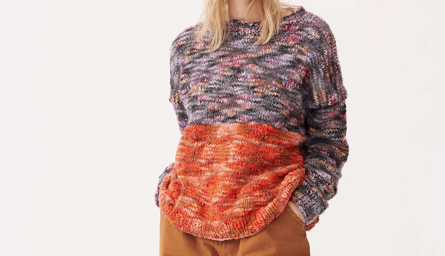 Strickanleitung Pullover aus Creative Wooly Waves Strickanleitung Pullover aus Creative Wooly Waves: Bunter Pullover mit grauem und orangefarbenem Muster, getragen von einer Frau.