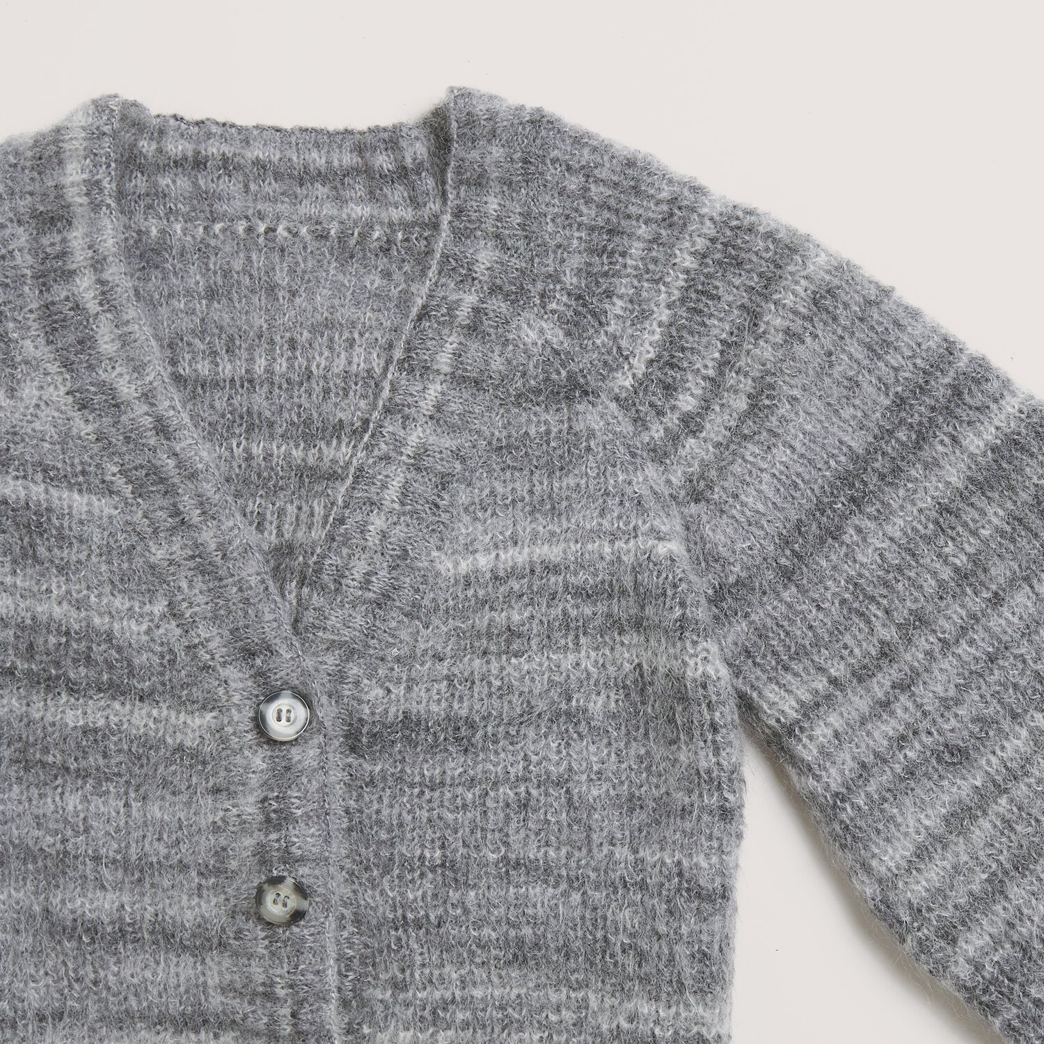 Fashion Meri Mohair Print 50g 275m Farbe Stone Grey von Rico Design Fashion Meri Mohair Print: Grauer Strickpullover mit V-Ausschnitt und Knöpfen, aus weichem Material von Rico Design. Ideal für kühle Tage.