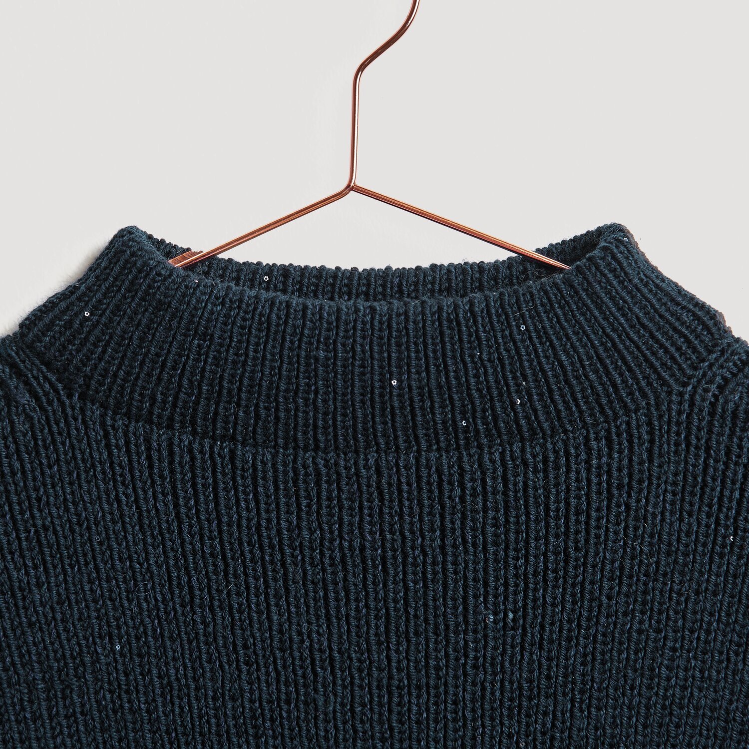 Essentials Merino dk Pullover in Marineblau, aus hochwertiger Wolle, auf einem Kupferbügel.
