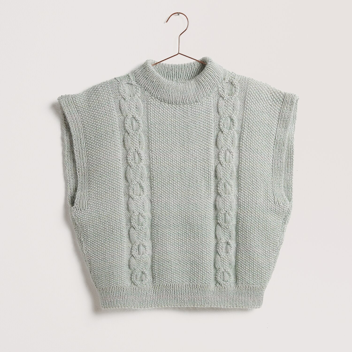 Strickset Pullunder Modell 16 aus Die Neue Masche No. 12 von idee. Creativmarkt Strickweste in Silbergrau mit Zopfmuster, ärmellos und rundem Kragen, auf einem Kleiderbügel.