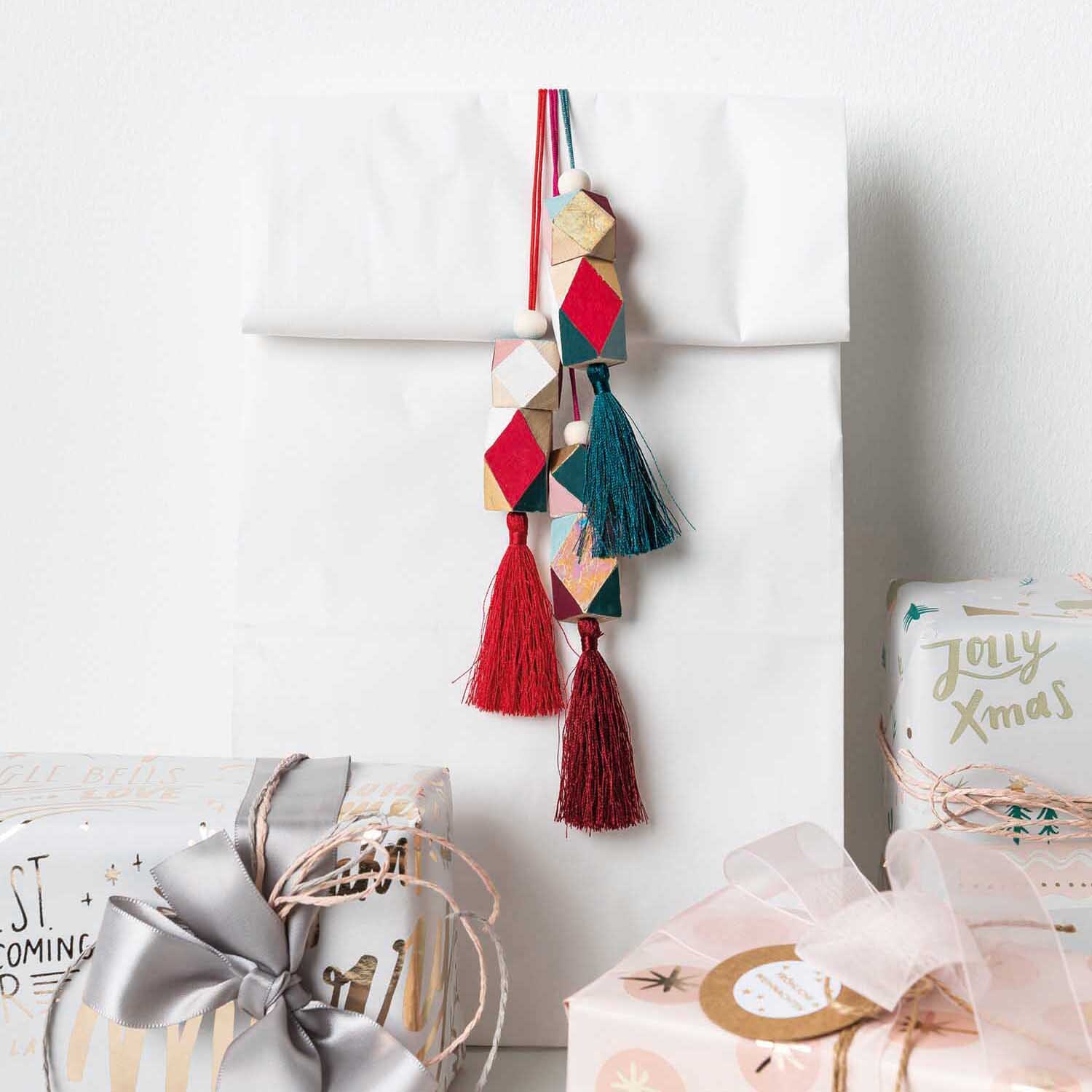 Holzperlen Diamant 3x2x2cm 3 Stück, dekorativ an Geschenkverpackung mit roten und blauen Quasten. Ideal für kreative Geschenkideen.