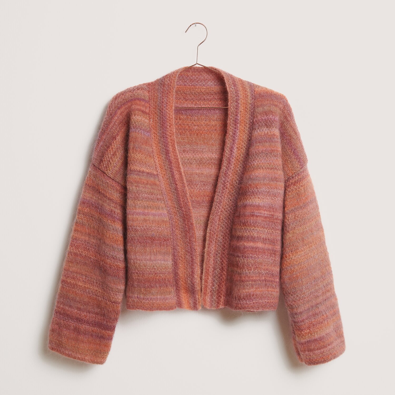 Fashion Meri Mohair Print 50g 275m Farbe Happy Sunrise von Rico Design Strickset Kimono-Jacke Modell 01 in warmen Rottönen, präsentiert auf einem Kleiderbügel. Ideal für den Winter.