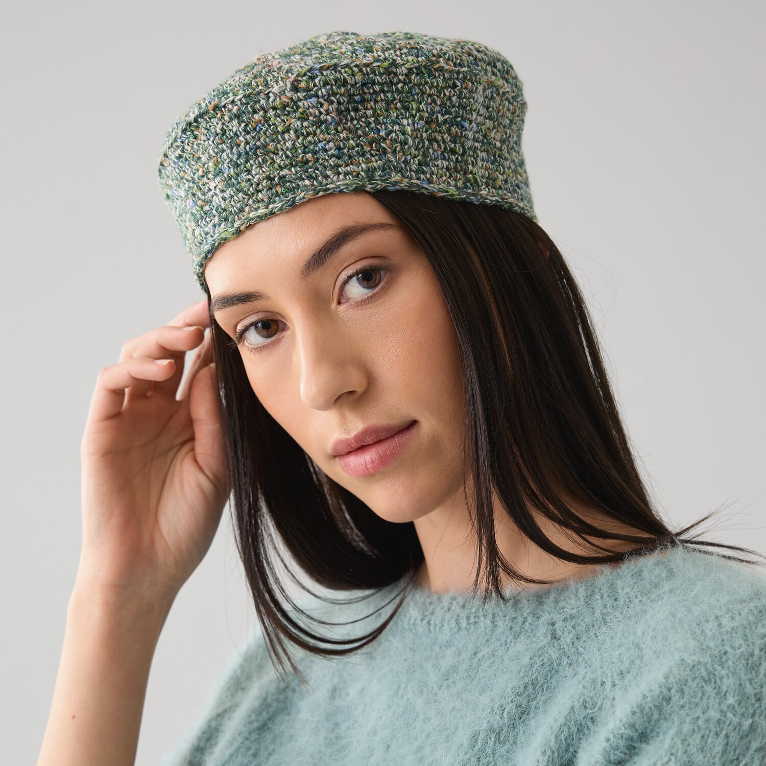 Häkelset Barett Modell 20 B aus Die Neue Masche No. 15: Frau trägt grünes Barett und Pullover.