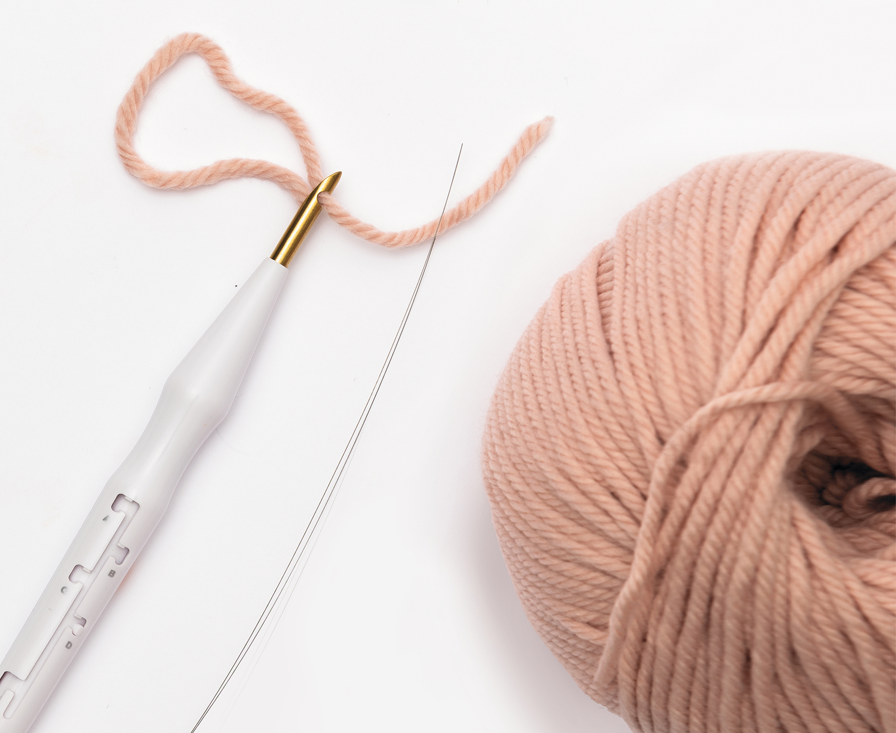 Punch Needle und rosa Wollknäuel auf weißem Hintergrund