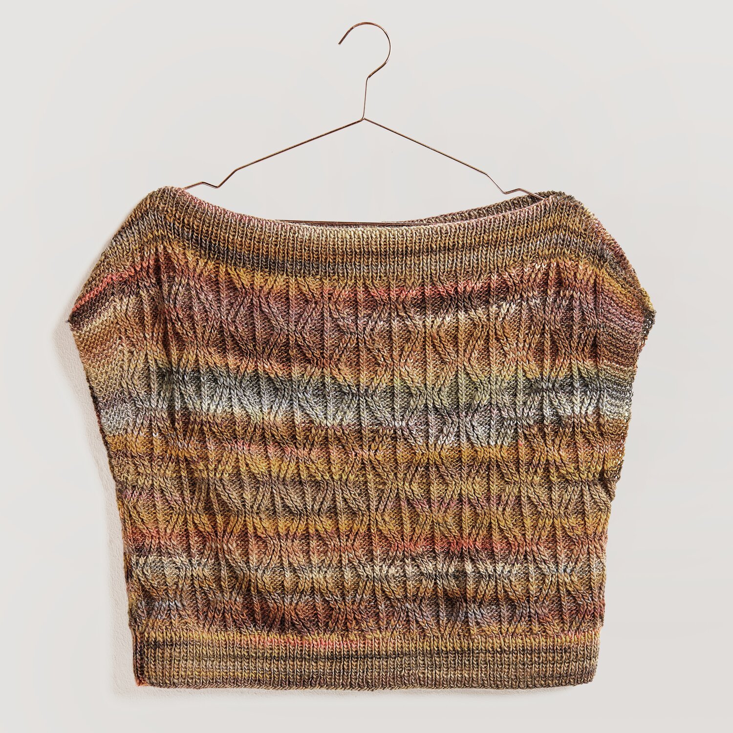 Strickset Top Modell 17 zeigt ein gestricktes Oberteil in warmen Herbsttönen, aufgehängt an einem Kleiderbügel.