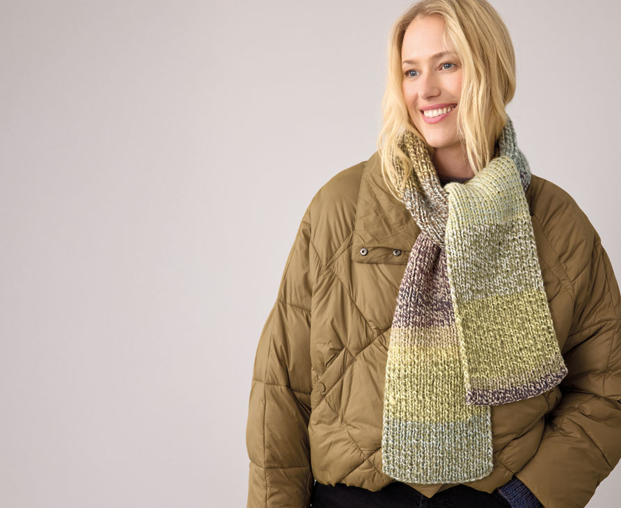 Frau trägt grünen Strickschal vor hellem Hintergrund