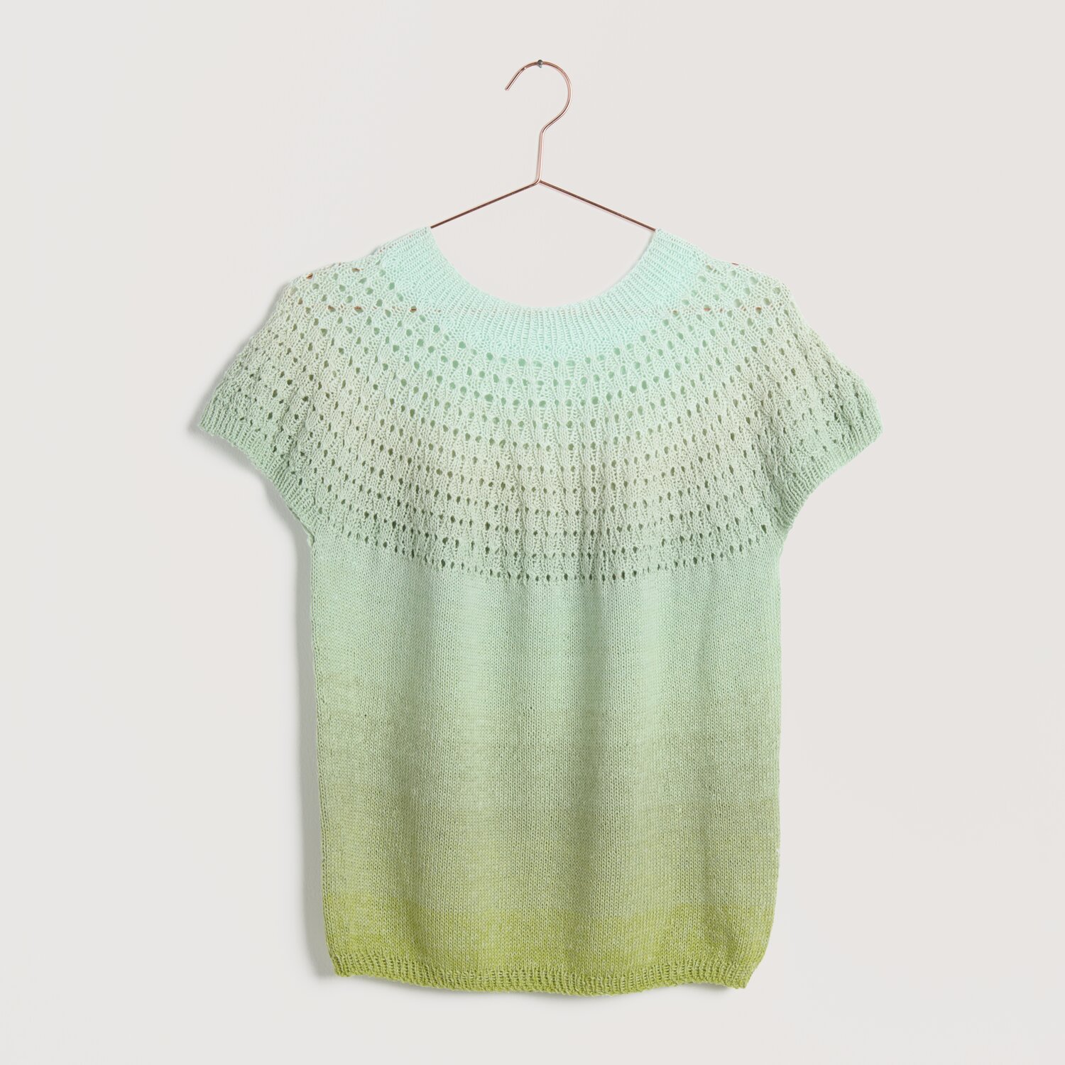 Strickset Shirt Modell 22 aus Lovewool No. 22, in sanften Aloe-Tönen, auf einem Kleiderbügel präsentiert. Ideal für Frühjahr-Sommer.