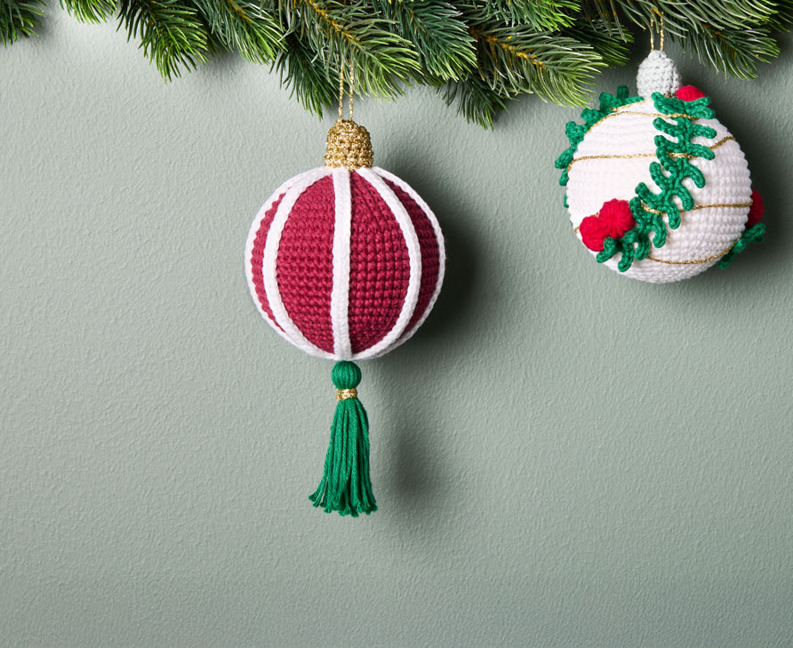 Gehäkelte Weihnachtskugeln hängen an Tannengirlande
