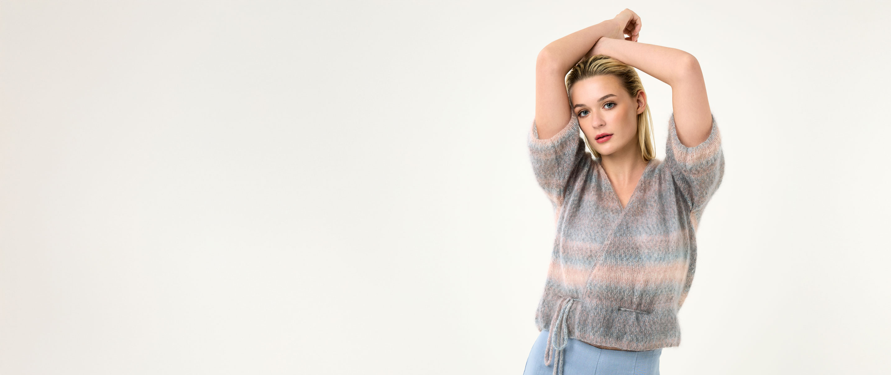 Model gestricktes Wickel-Shirt im Pastellprint vor einem hellen Hintergrund.