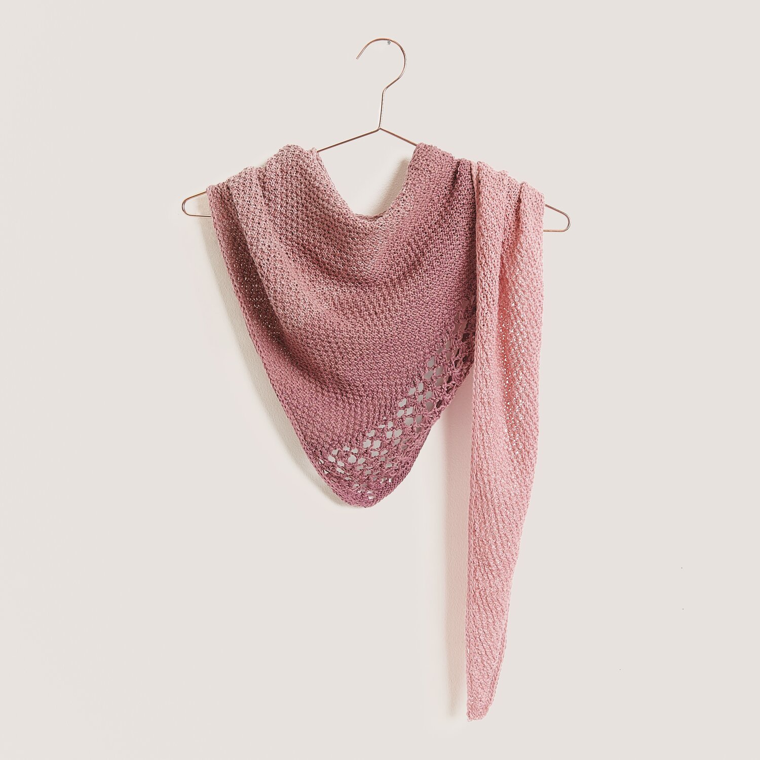 Strickset Tuch Modell 09 aus Tücher Special von Rico Design Strickset Tuch Modell 09 aus Tücher Special in Altrosa, präsentiert auf einem Kleiderbügel.