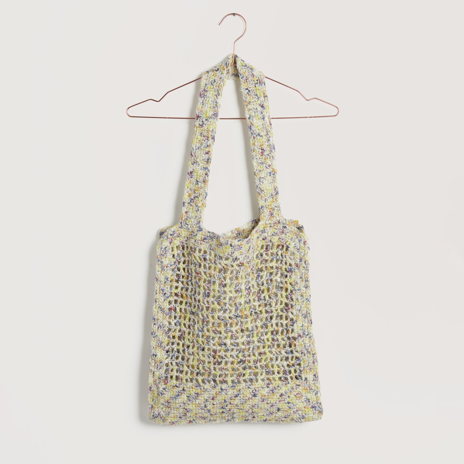 Häkelset Tasche Modell 28 aus Lovewool No. 22, beige-gelb, auf einem Kleiderbügel präsentiert.