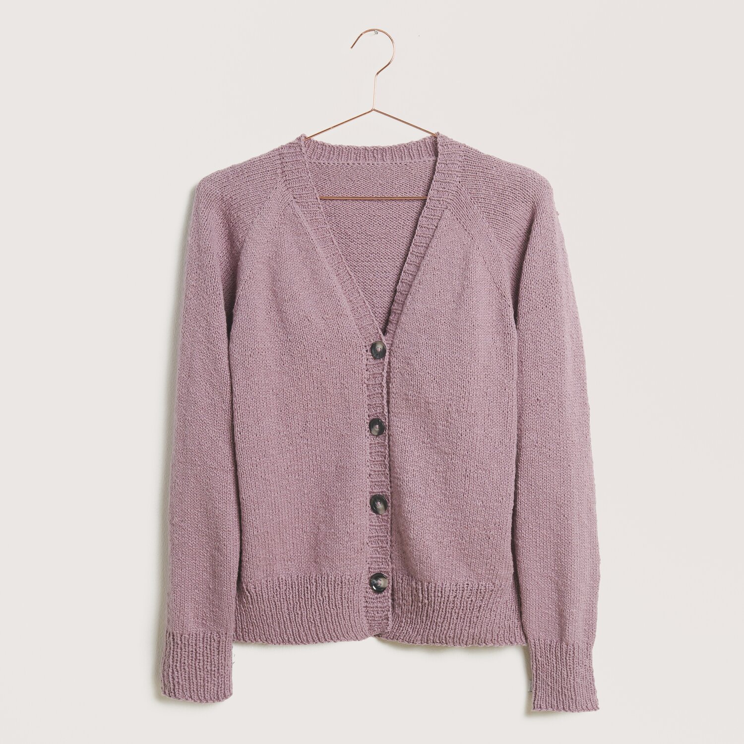 Strickset Cardigan Modell 10 aus Die Neue Masche Nr. 9: Lila Strickjacke mit Knöpfen, ideal für Frühjahr-Sommer, präsentiert auf einem Kleiderbügel.