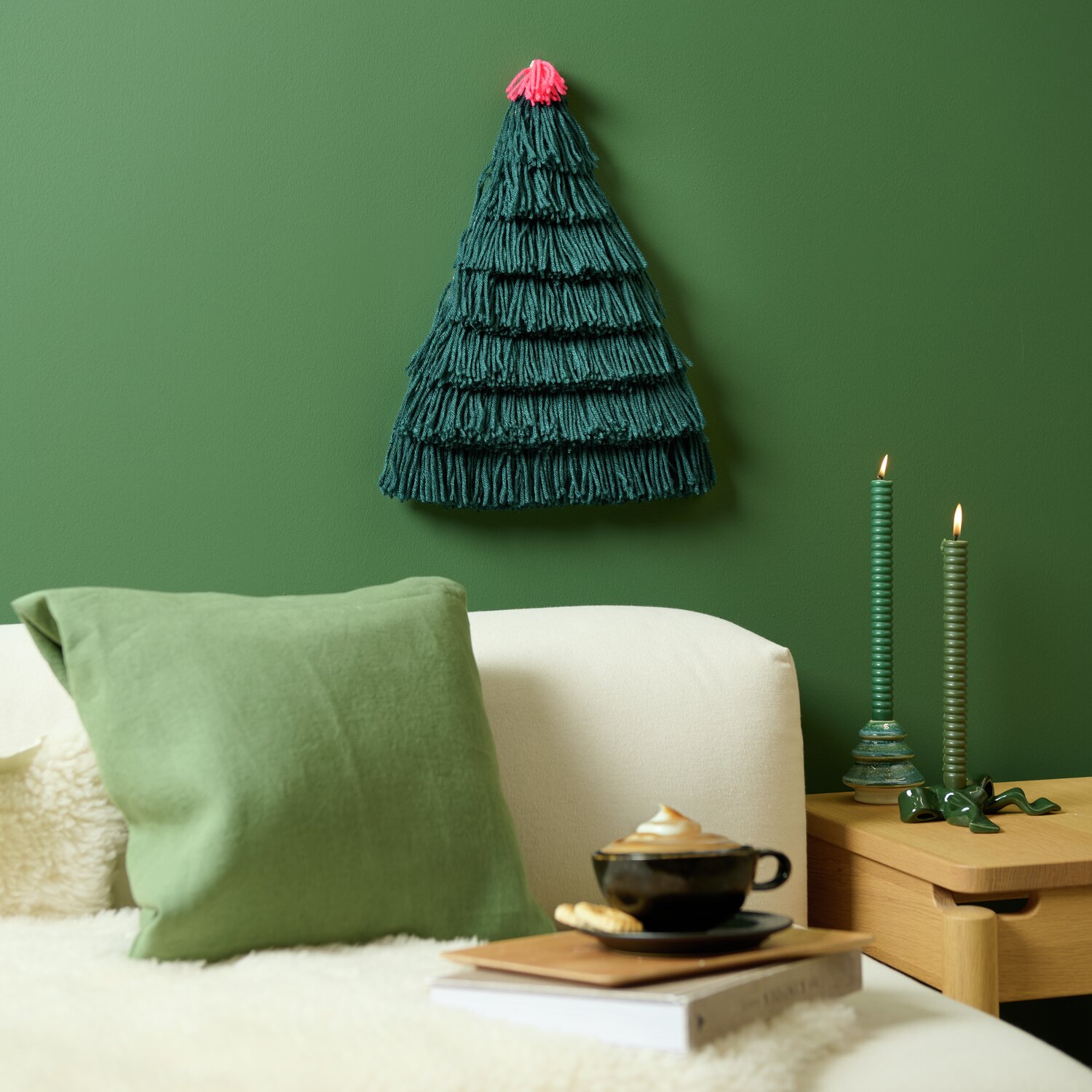 Rico Hooki Hooki Knüpfset Wandbehang Tannenbaum, grün, 44x48cm, an grüner Wand über Sofa.