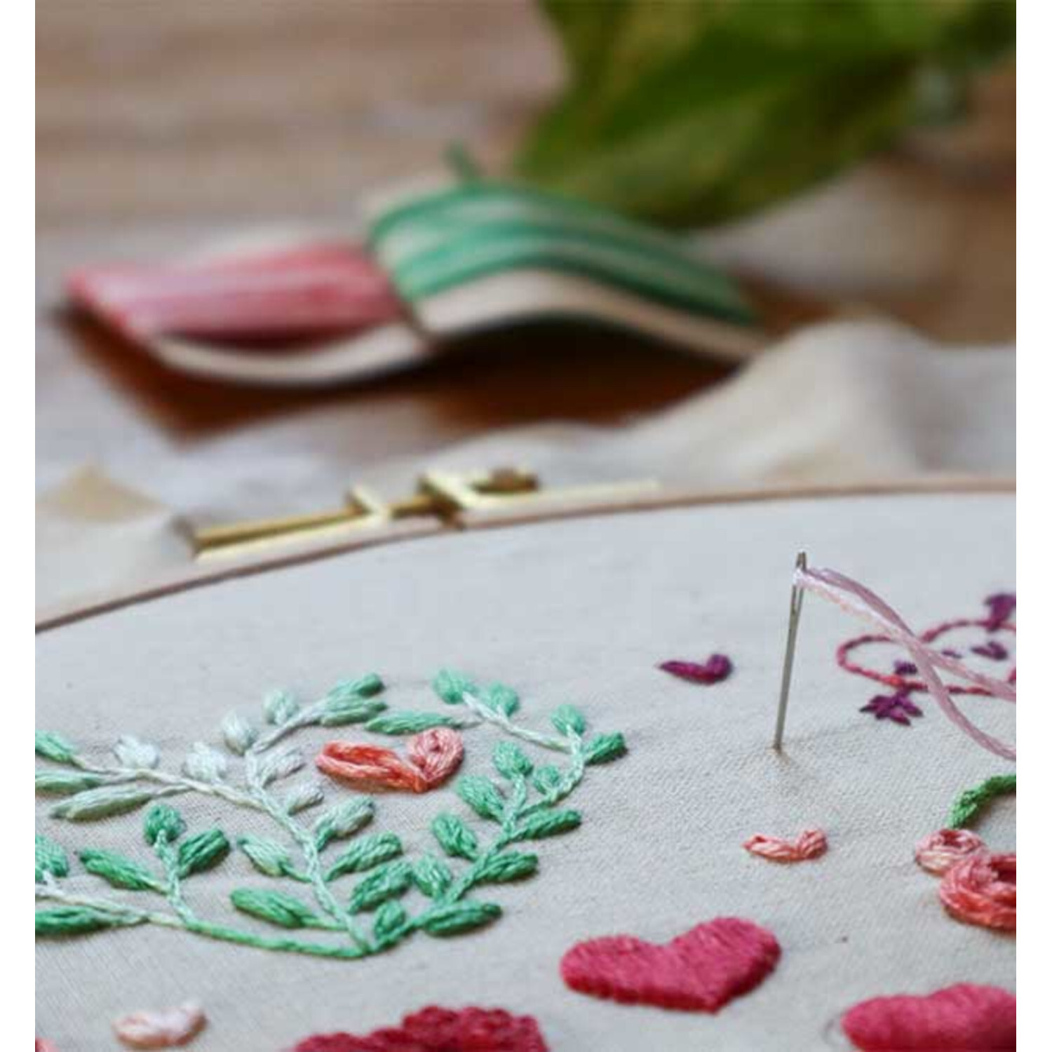 Sticken. Die Motivsammlung: Nahaufnahme eines Stickrahmens mit bunten Herz- und Blattmotiven.