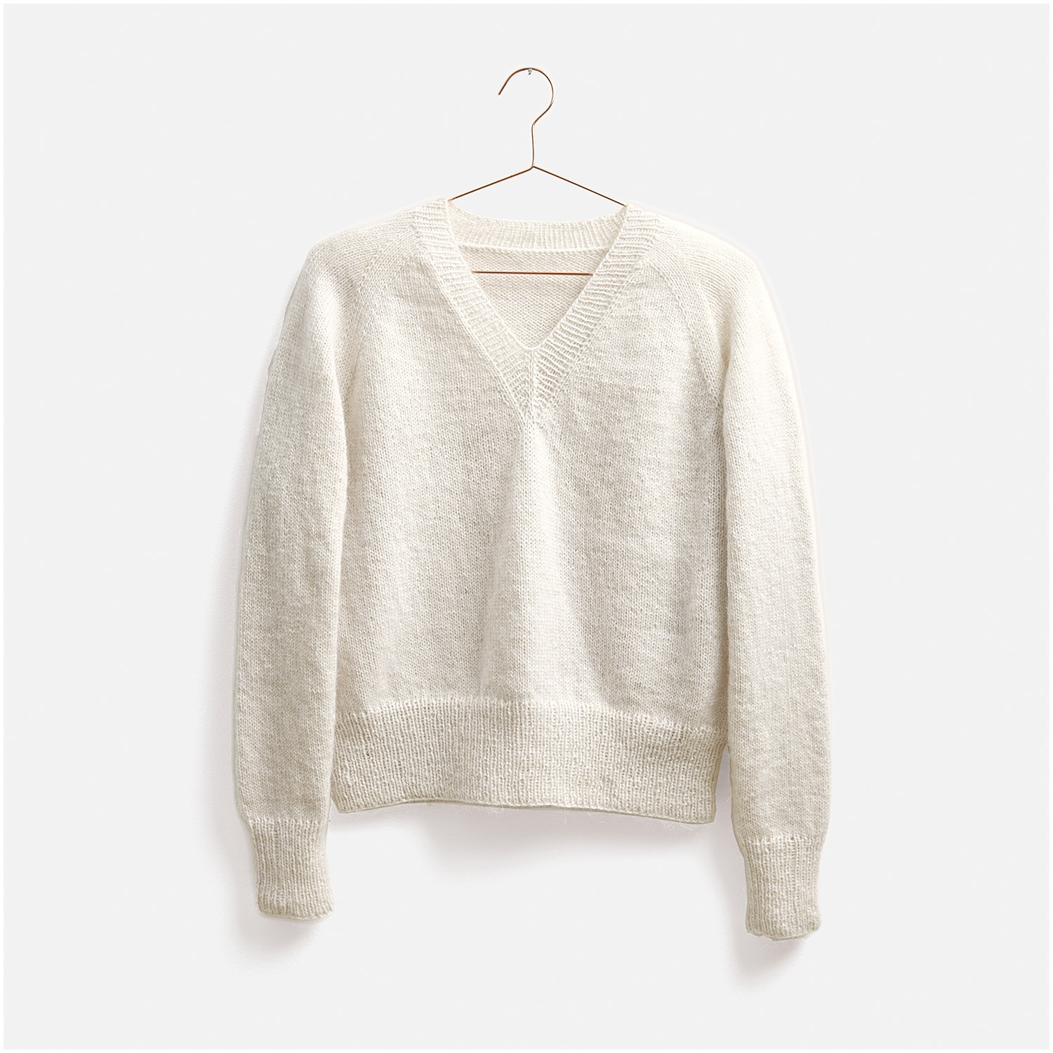 Weißer Strickpullover, Modell 11, aus dem Top Down Knitting Special Nr. 2. Der Pullover hat einen V-Ausschnitt und lange Ärmel, präsentiert auf einem Kleiderbügel. Ideal für stilvolle, gemütliche Outfits.