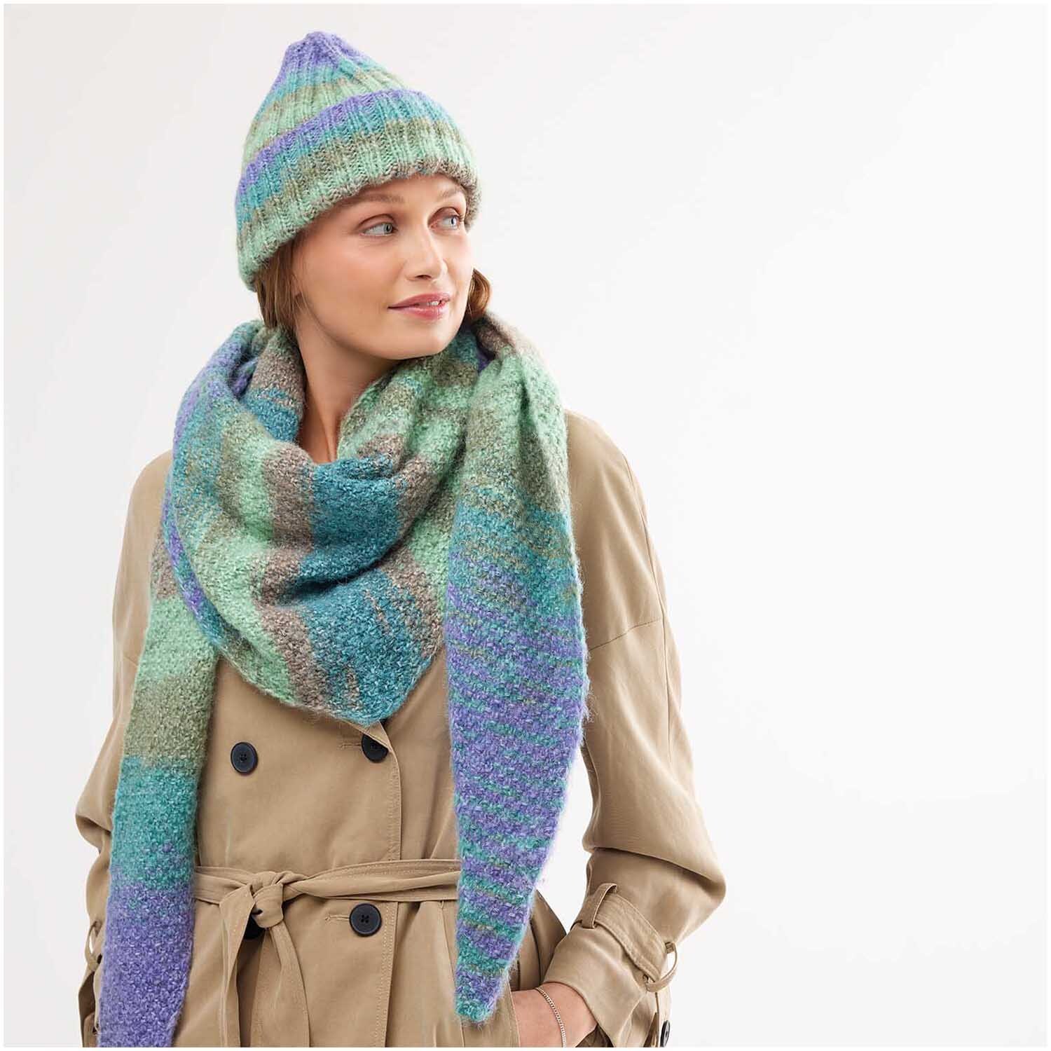 Strickset Dreieckstuch Modell 21 aus Creative Painted Power Special: Frau mit buntem Schal und Mütze in Pastelltönen, trägt beigen Mantel.