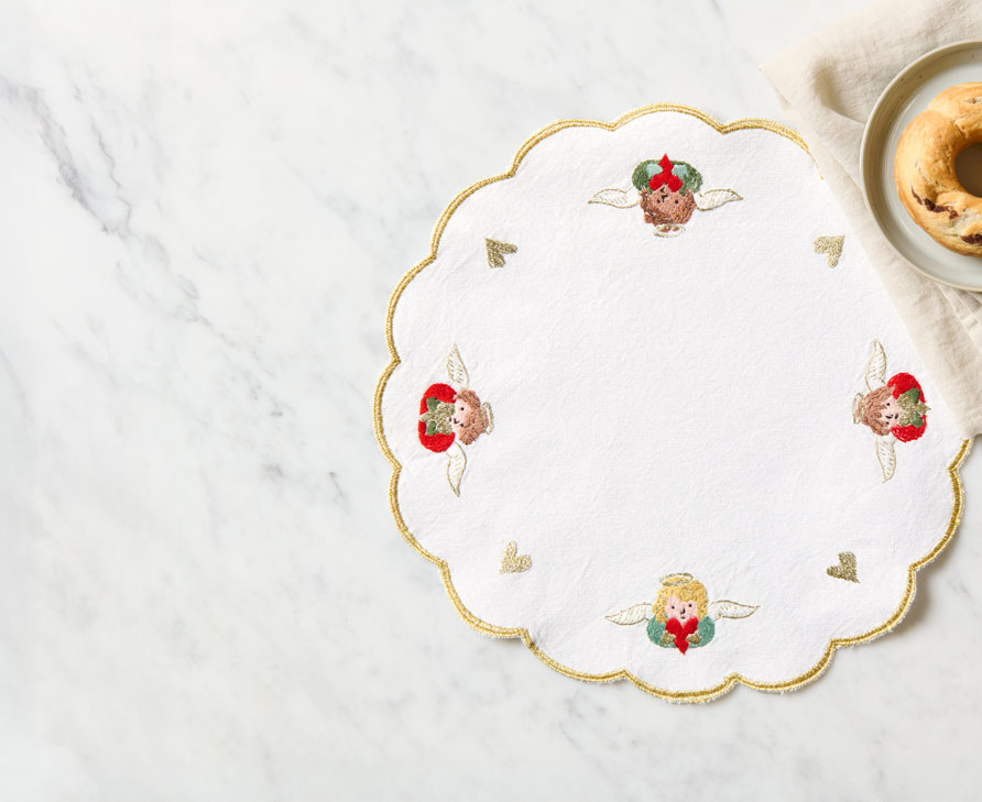 Besticktes Weihnachtsdeckchen liegt auf Tisch