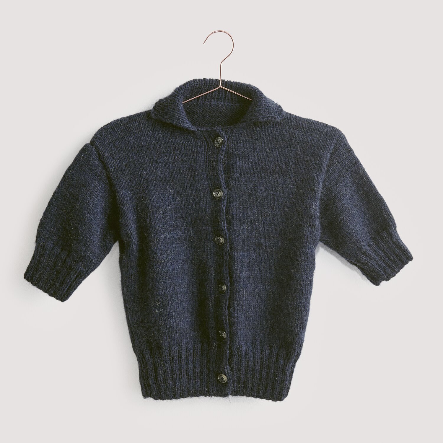 Strickset Jacke Modell 14 aus Luxury Knits: Dunkelblaue Strickjacke aus Premium Natural Fibres, hängend an einem Kleiderbügel.