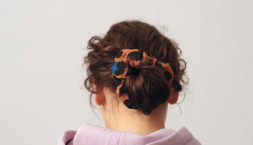 Nähanleitung für Scrunchies aus Stoff: Frau mit lockigem Haar trägt bunten Scrunchie im Dutt.