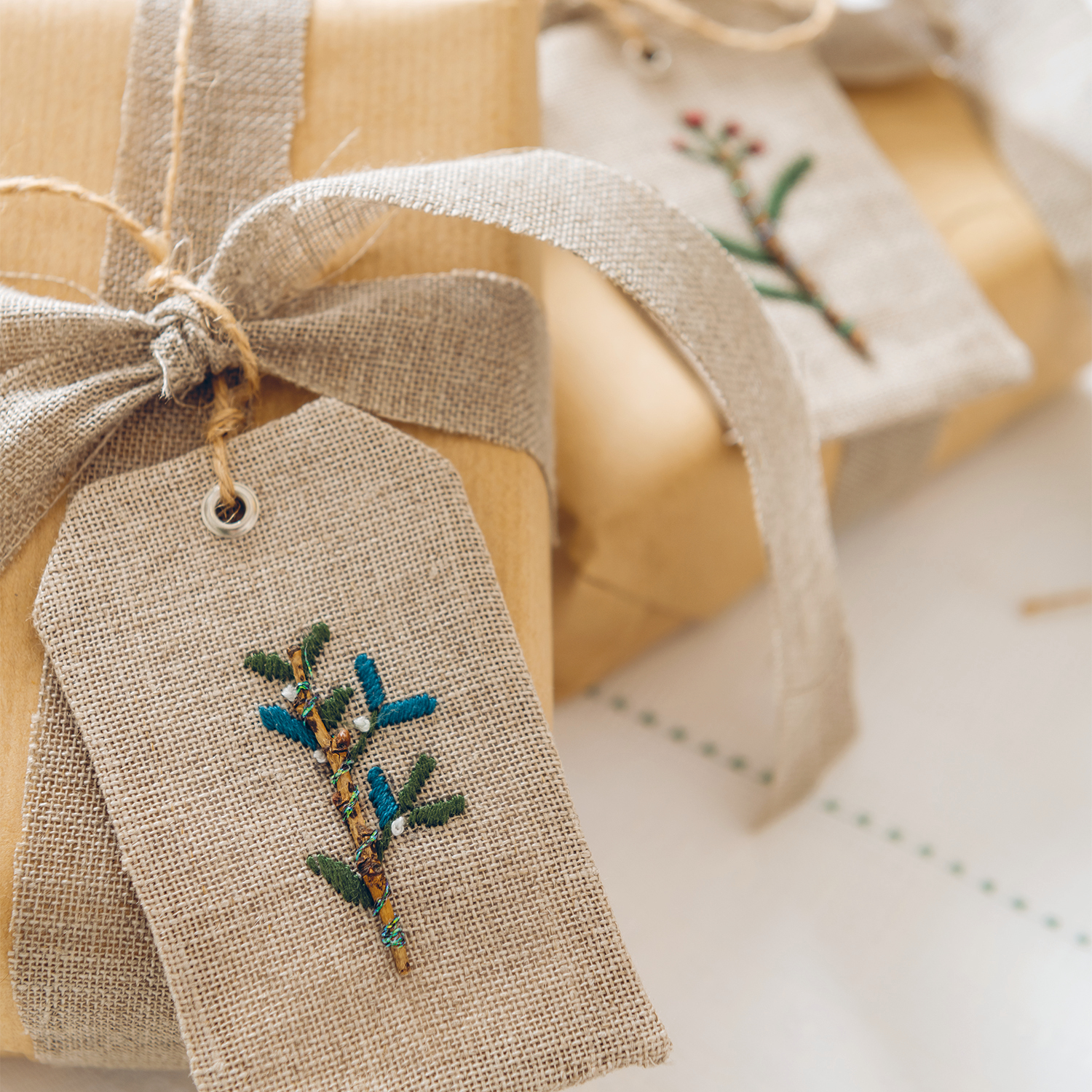 Stickanleitung Geschenkanhänger für Weihnachten Stickanleitung Geschenkanhänger für Weihnachten: Handgemachte Anhänger mit Stickerei auf Leinen, dekoriert mit Zweigen, ideal für festliche Geschenke.