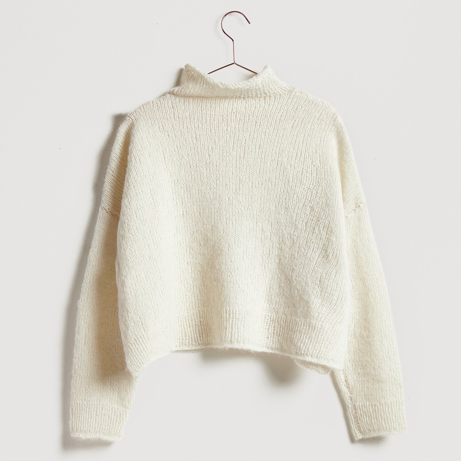 Luxury Alpaca Cotton Fusion Pullover in Creme, gestrickt aus weicher Wolle, hängt an einem Kleiderbügel.