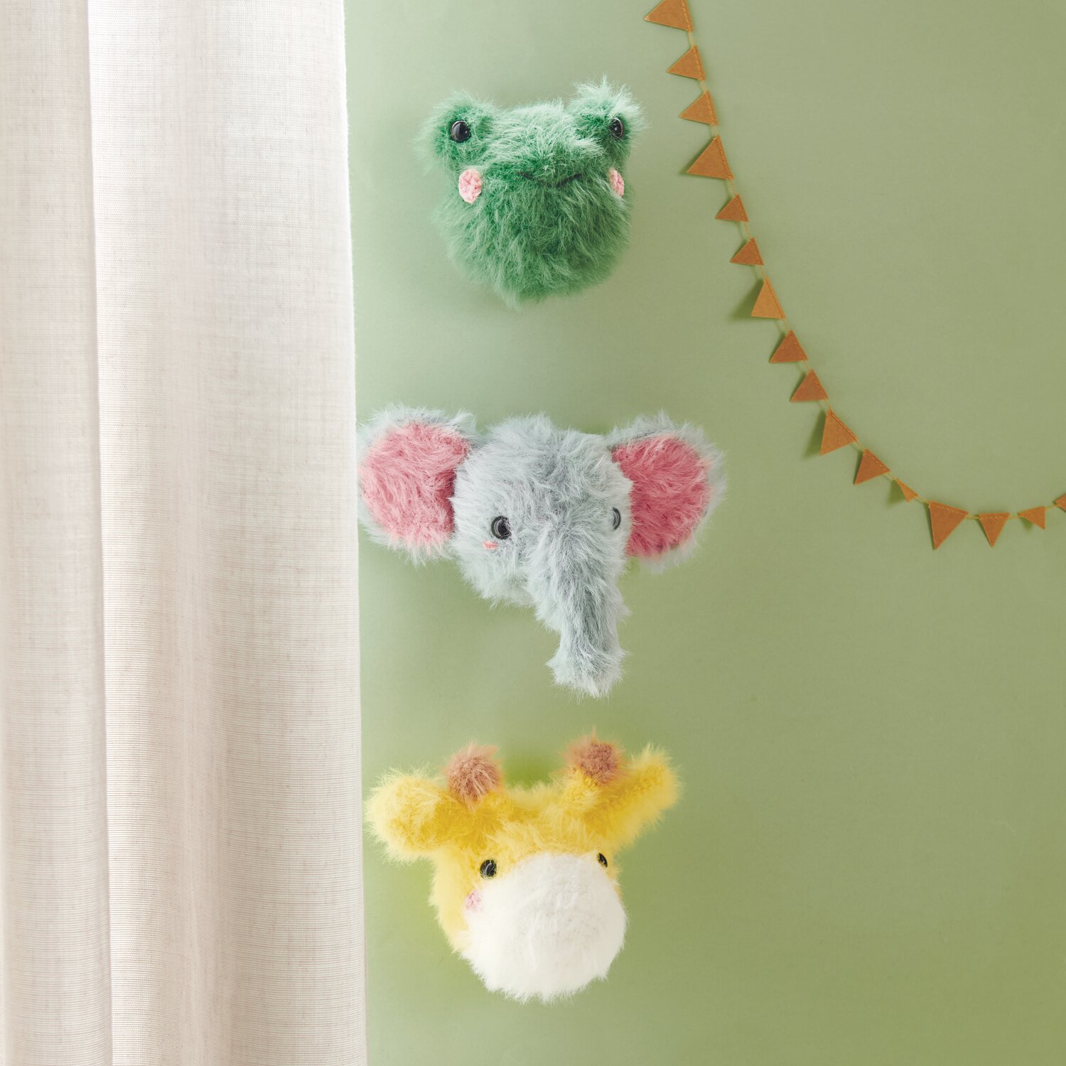Creative Ricorumi dk 25g Farbe Patina von Rico Design Ricorumi Furry Animals: Drei gehäkelte Tierköpfe in Grün, Blau und Gelb an einer grünen Wand.