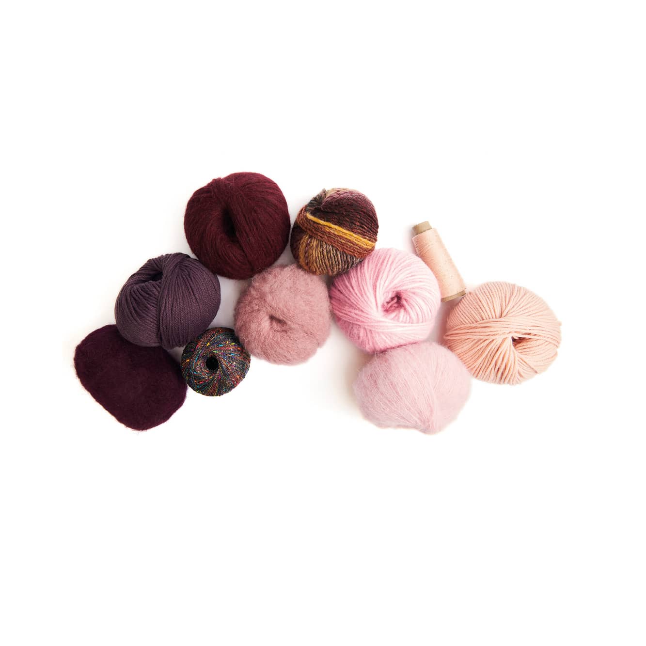 Nebeneinander liegende Wollknäuel in Dunkelrot und Rosatönen