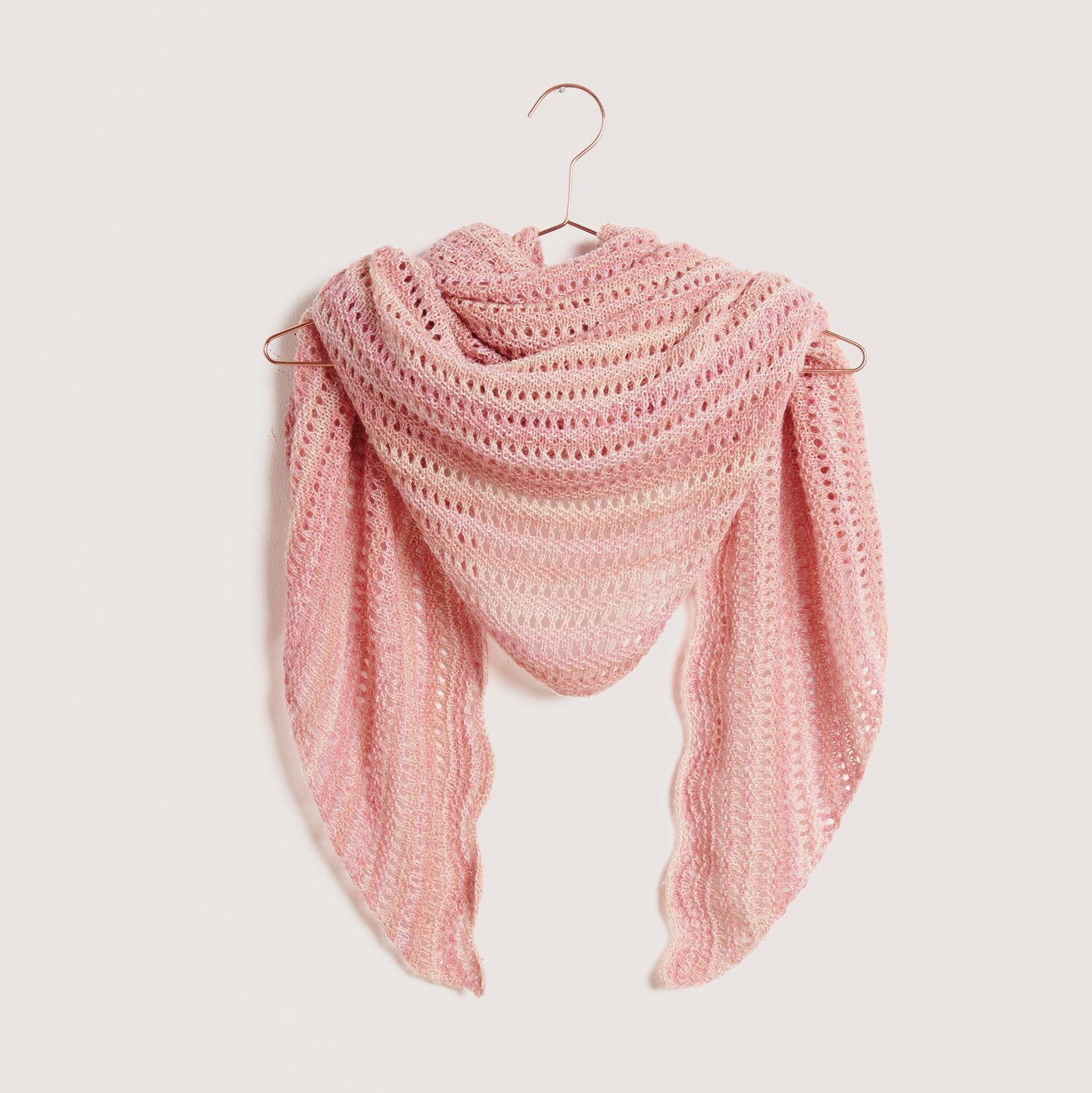Strickset Dreieckstuch Modell 06 einfädig aus Die Neue Masche Nr. 9 von idee. Creativmarkt Strickset Dreieckstuch Modell 06 in Rosa, elegant drapiert auf einem Kleiderbügel. Ideal für Frühling und Sommer.