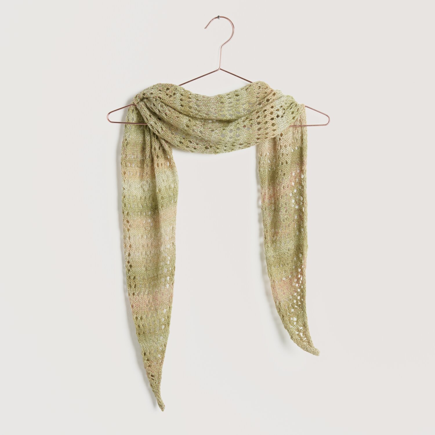 Strickset Tuch Modell 03 aus Lovewool No. 22, gehäkelt in sanften Jade- und Pfirsichtönen, hängt elegant auf einem Kleiderbügel.