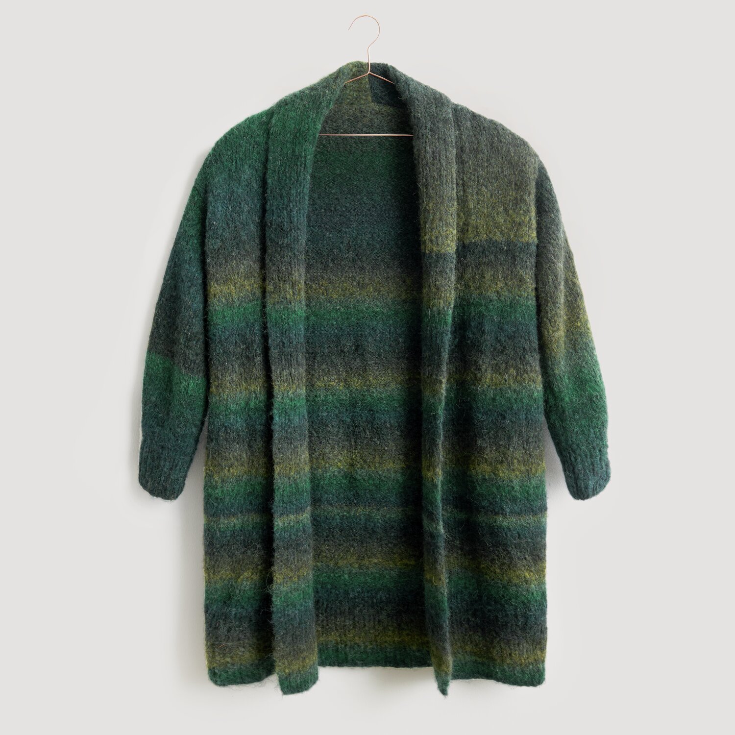 Strickjacke in Grün- und Blautönen, hängend an einem Kleiderbügel. Modell Legeware, ideal für kühle Tage. Weiches Material, perfekt für gemütliche Anlässe.