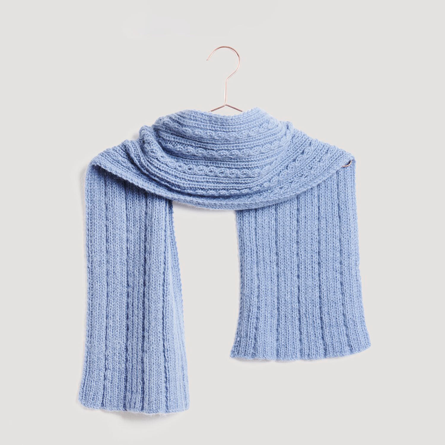 Stirnband und Schal in hellblauer Strickoptik, präsentiert auf einem Kleiderbügel. Marke: Modell Legeware. Perfekt für kalte Tage, stilvoll und warm.