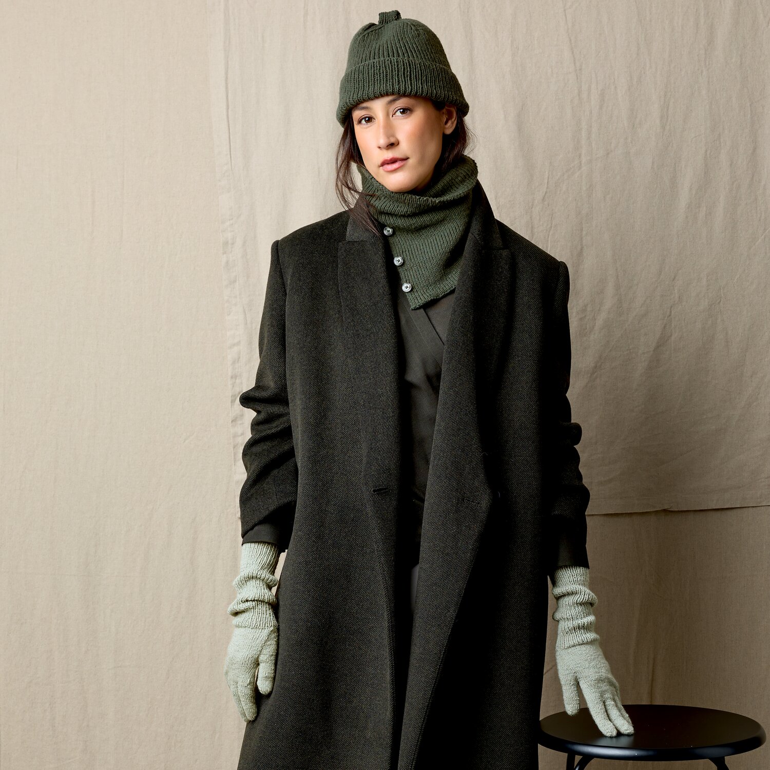 Strickset Mütze Modell 02 aus Luxury Knits Little Pieces, winterliches Set mit gerippter Beanie, passendem Schal und warmen Handschuhen an Frau im Mantel