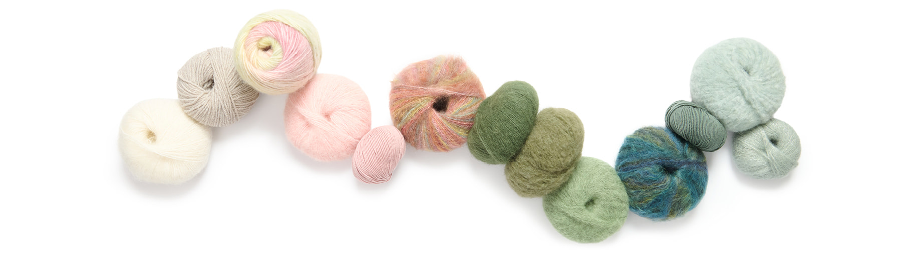 Verschiedene Garne farblich sortiert und aneinandergereiht. Flatlay von Produkten.