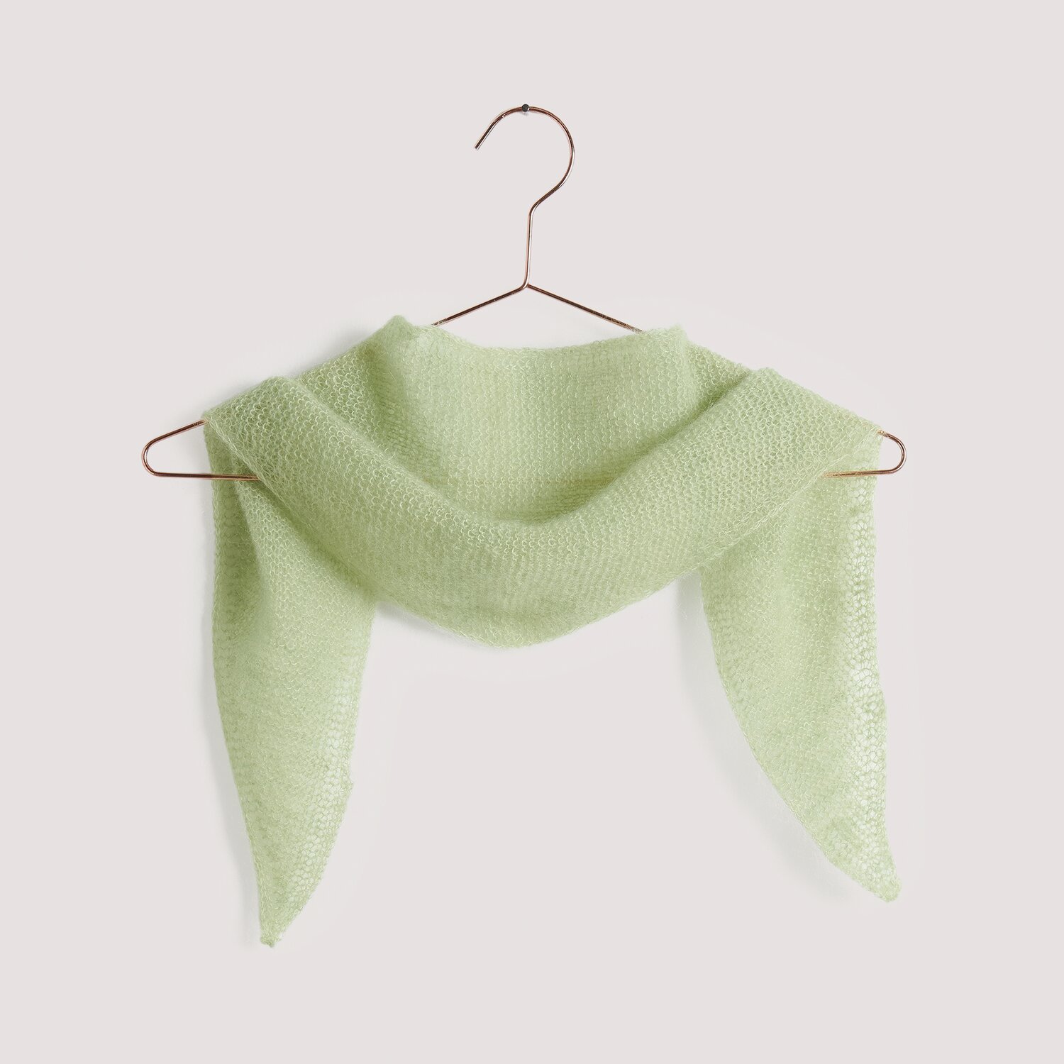 Strickset Dreieckstuch Modell 12 B aus Die Neue Masche No. 15, pastellgrün, auf einem Kleiderbügel.