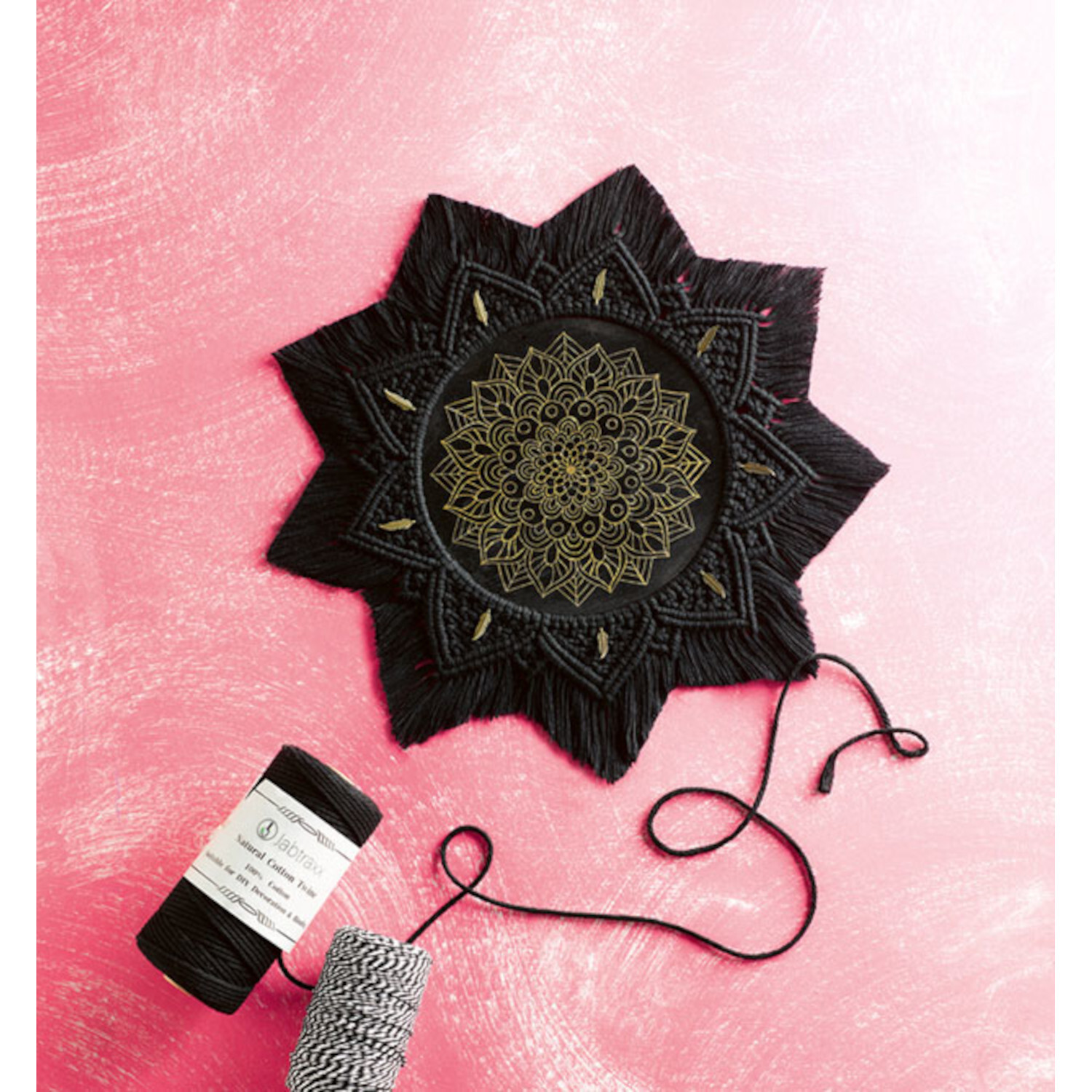 Mindful Mandala-Makramee auf rosa Hintergrund mit schwarzem Garn und detailliertem Muster.