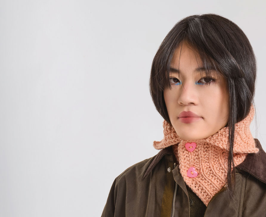 Frau trägt apricotfarbenen Schalkragen mit pinken Herz-Knöpfen