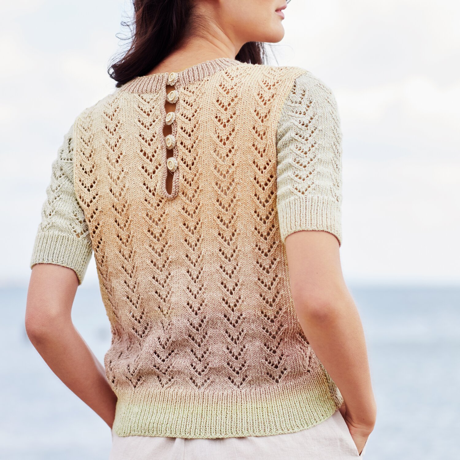 Strickset Shirt Modell 10 aus Lovewool No. 22, pastellfarben, mit Knopfleiste am Rücken, am Meer getragen.