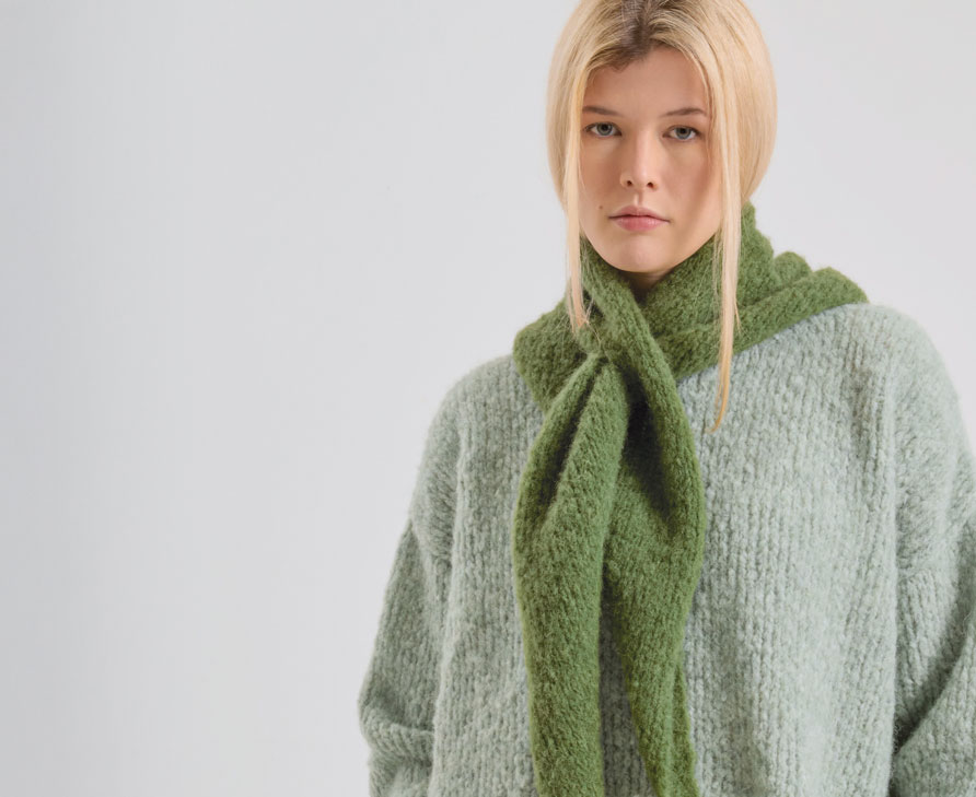Frau trägt hellgrünen Strickpullover und moosfarbenen Strickschal
