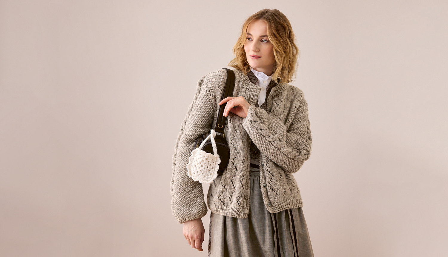 Strickanleitung Trachtenjacke aus Soft Alpaca Trachtenjacke aus Soft Alpaca: Elegante, graue Jacke mit Zopfmuster, kombiniert mit einem weißen Hemd und grauem Rock. Ideal für stilvolle Anlässe.
