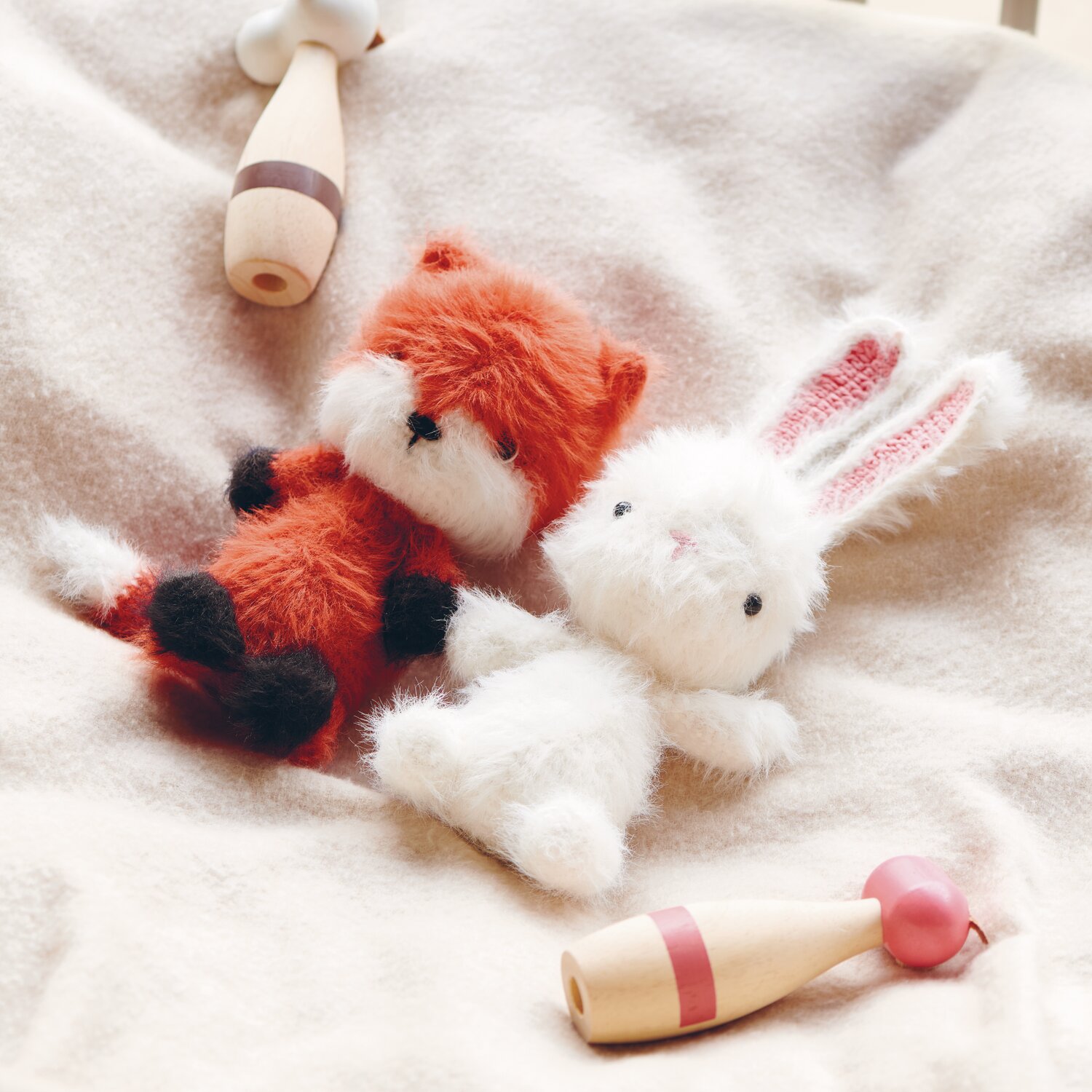Creative Ricorumi dk 25g Farbe Fuchs von Rico Design Ricorumi Furry Animals: Zwei weiche Plüschtiere, ein Fuchs in Koralle und ein weißer Hase, auf cremefarbenem Stoff.