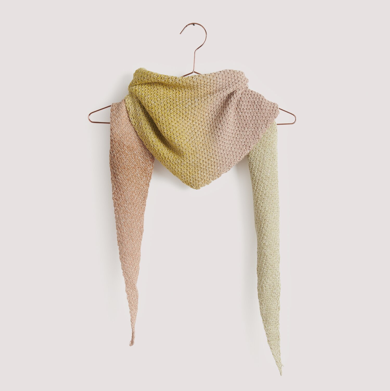 Strickset Dreieckstuch Modell 16: Handgestricktes Tuch in sanften Pastelltönen auf einem Kleiderbügel. Ideal für stilvolle Akzente.
