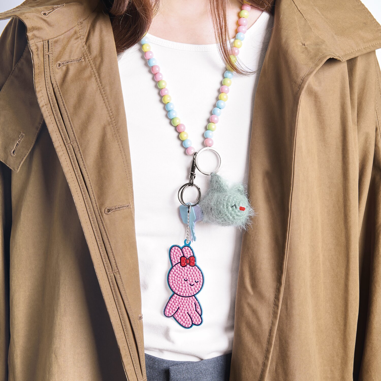 Ricorumi Häkelset Schlüsselanhänger - Chingu Sky: Frau mit buntem Schlüsselanhänger und beigem Mantel.