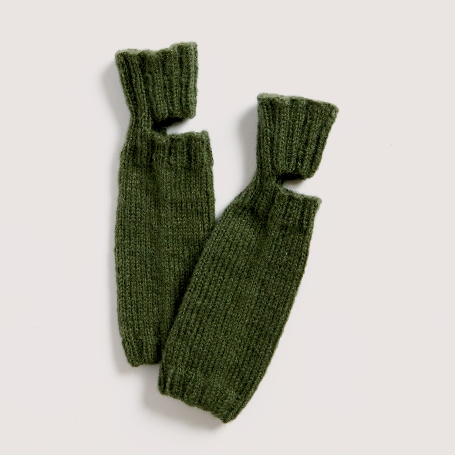 Strickset Stulpen Modell 06 aus Luxury Knits Little Pieces, lange grobgestrickte Armstulpen in dunklem Olivgrün mit Daumenloch, flach auf hellem Hintergrund platziert