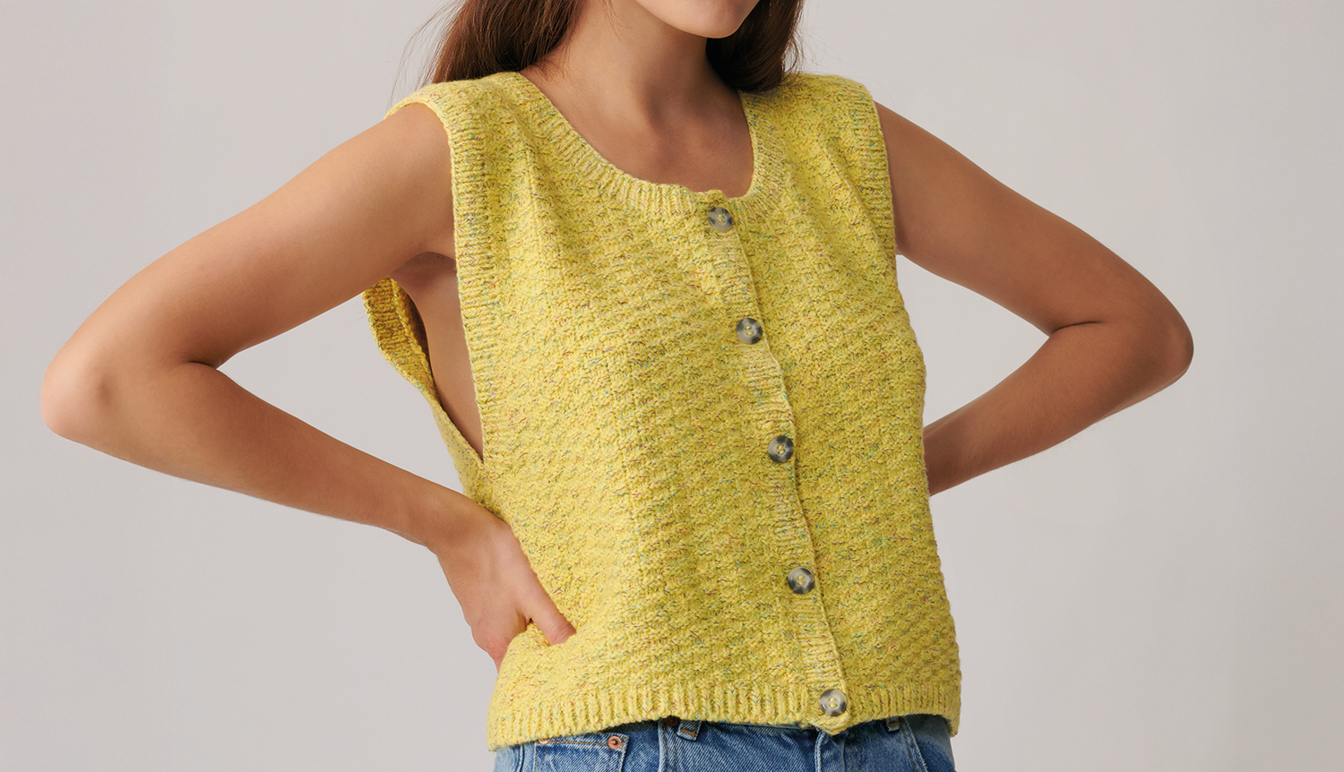 Strickanleitung Weste aus Fashion Cottony: Gelbe, ärmellose Weste mit Knöpfen, getragen von Frau.