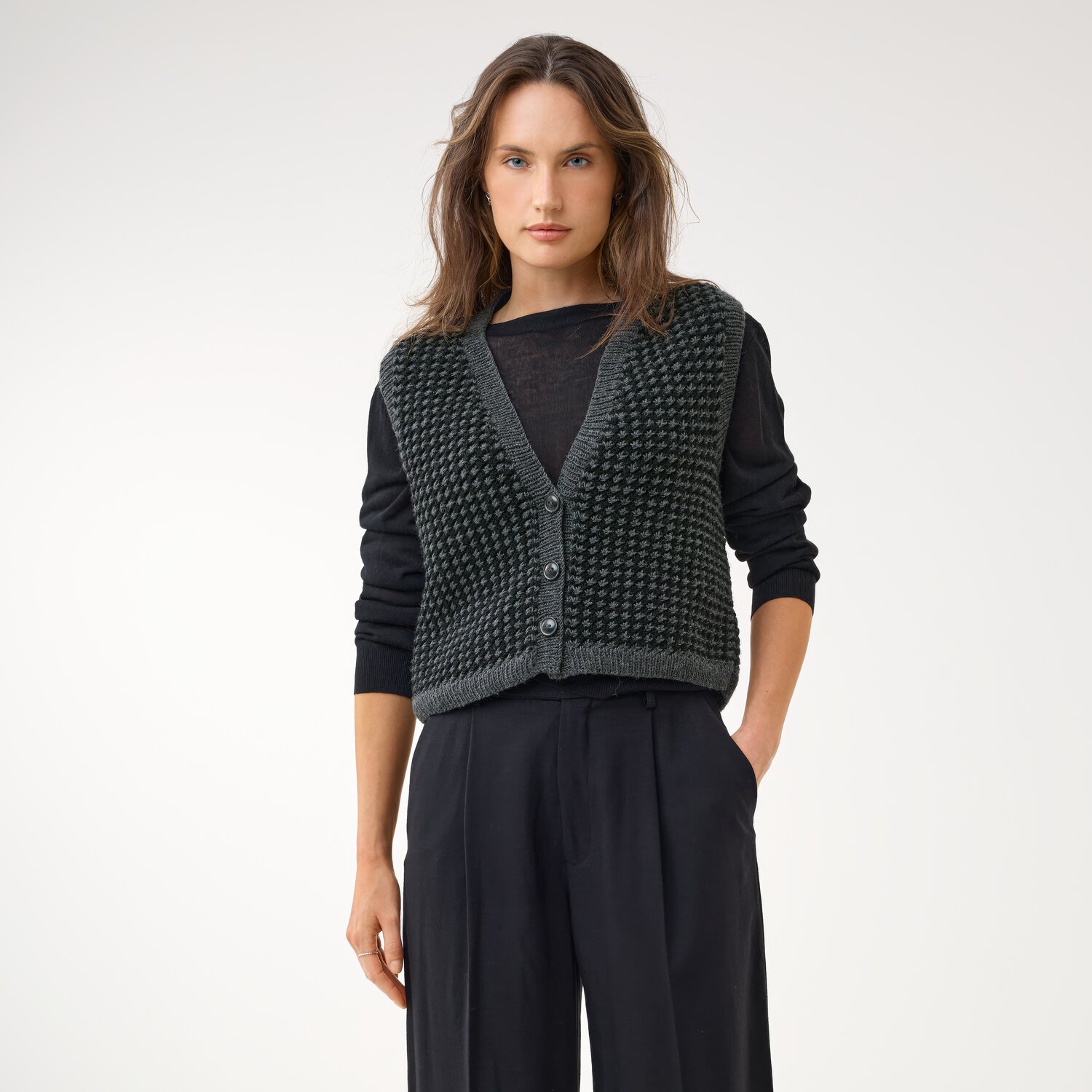 Strickset Weste Modell 02b aus Die Neue Masche No. 16, ärmellose grobgestrickte Knopfweste in dunklem Ton über schwarzem Langarmshirt, modern kombiniert mit weiter Hose