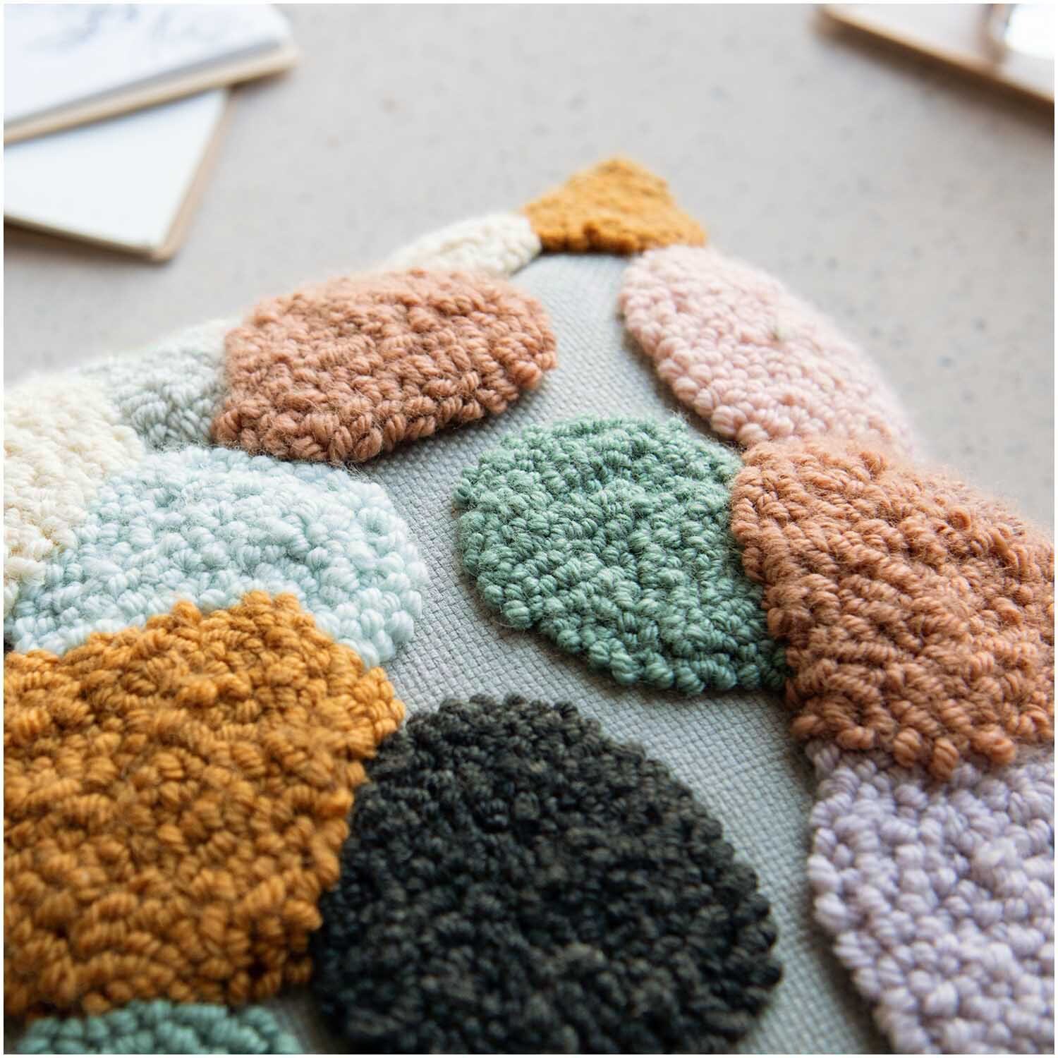 Punch Needle Packung Kissen Punkte bunt zeigt ein detailreiches, farbenfrohes Muster von Rico Design.